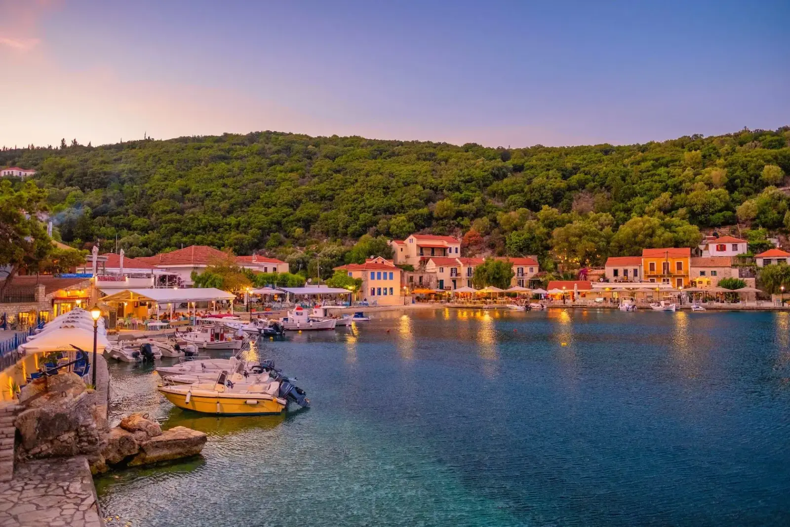Colourful harbour village on Ithaca at dusk, boats moored along the quay