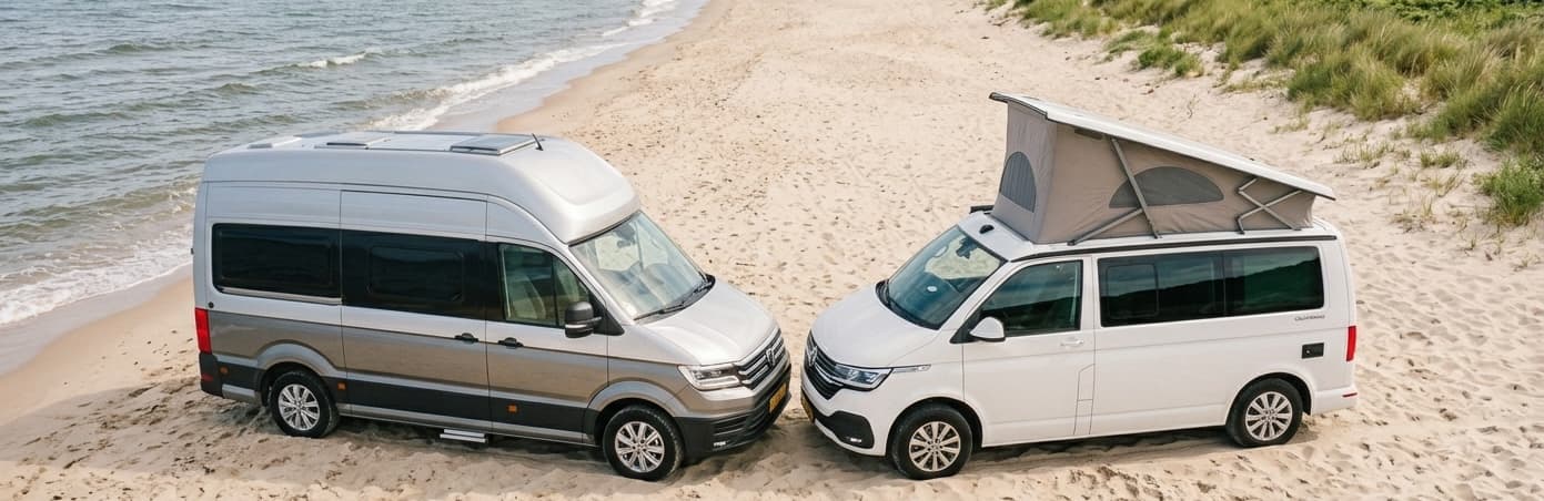 VW T6 campervan navigating a narrow stone-walled road through a traditional Greek village